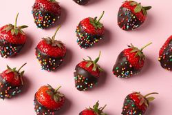 Chocolate fondue. Flat lay with strawberry in chocolate on pink background
