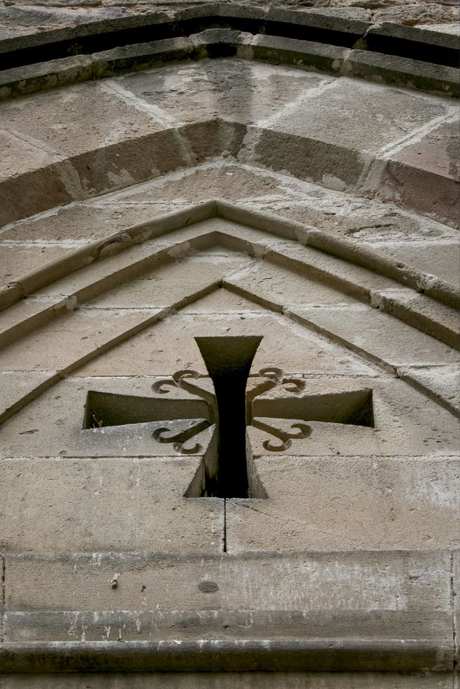 A real Spanish door with a cross. Catholic cross in Gothic style on a historical building