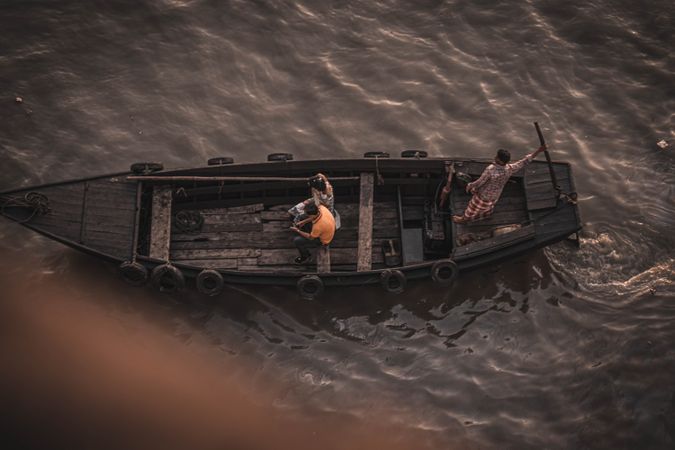 Top view of men on brown boat during sunset