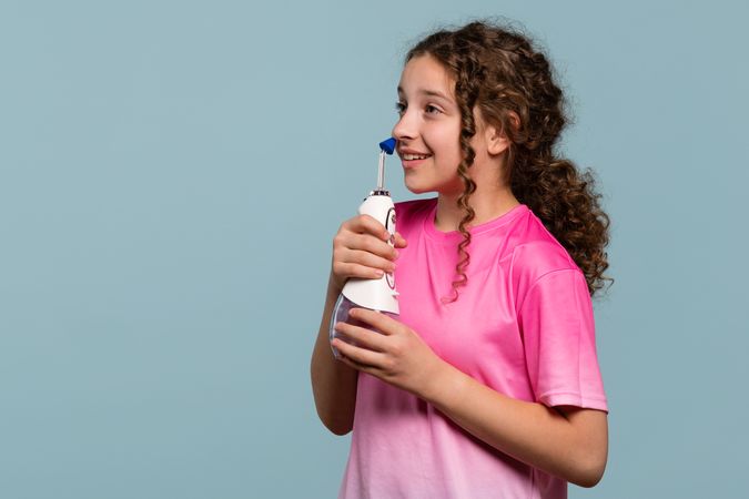 Smiling young girl using an oral irrigator