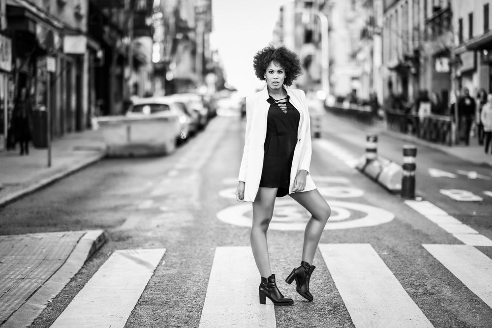 B&W female in short dress and blazer standing in the middle of street