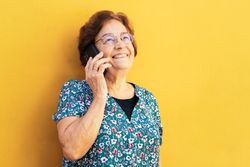 Cheerful older woman on a call outdoors