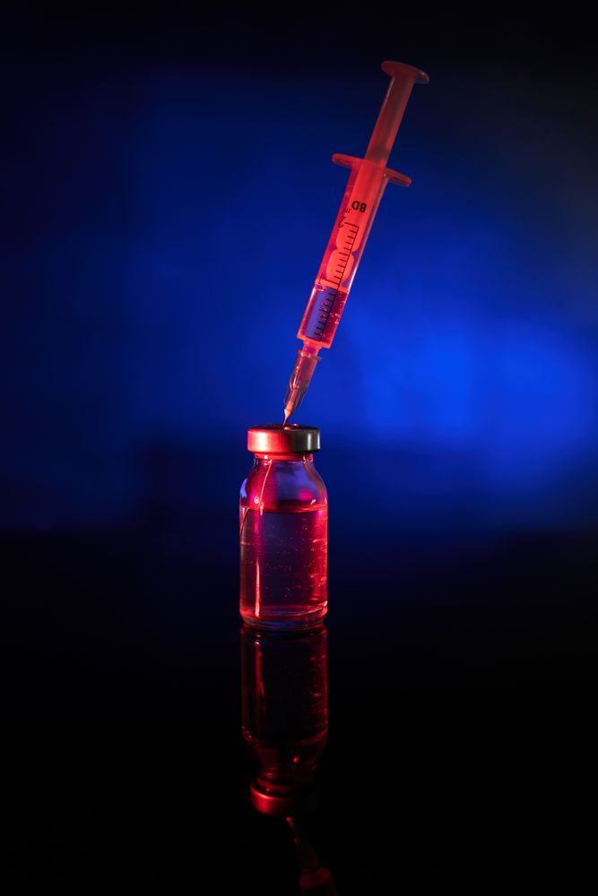 Red medical injection with COVID vaccine in studio