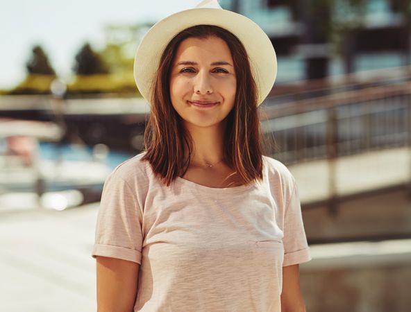 Portrait of woman standing in hat on sunny day
