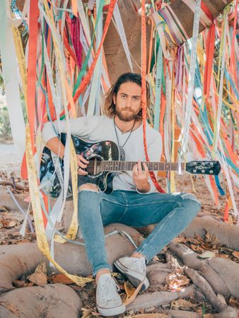 Man sitting under tree playing guitar