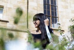 Portrait of beautiful young woman smiling seen behind a hedge
