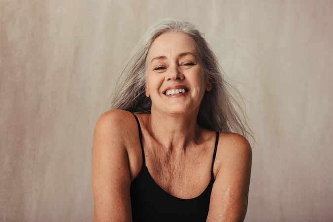 Older woman smiling in bikini top in a studio
