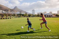 Woman playing football with her son in a playfield 0KMgVz