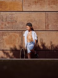 Stylish preteen skater standing outside building