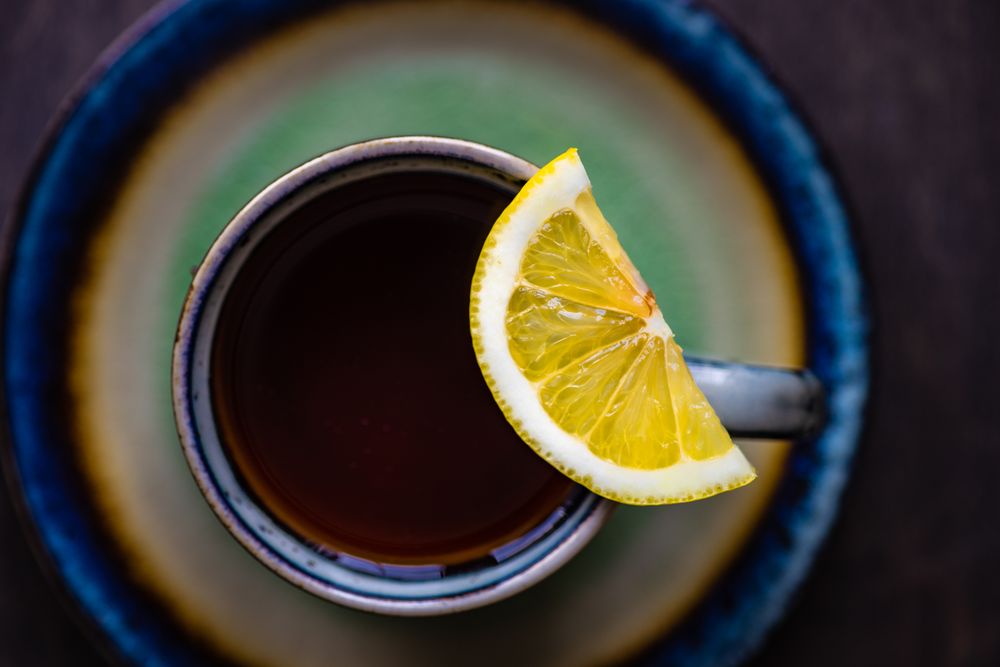 Top view of cup and saucer of tea and lemon slice