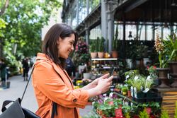 Content woman taking photo of flowers in garden center