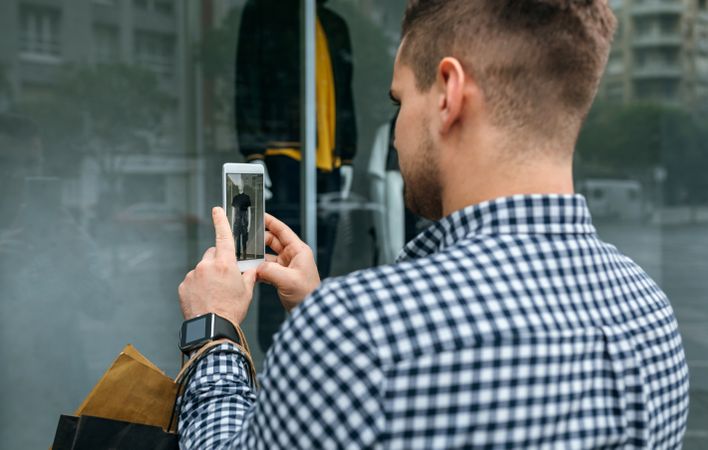 Man taking a photo of a shop window of a store