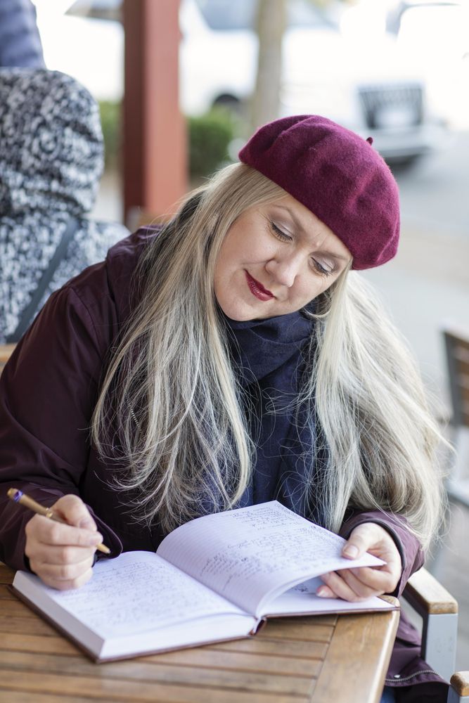 Older woman writing in a notebook at a cafe