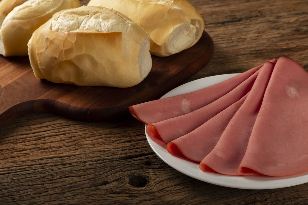 Sliced mortadella with breads on the table.