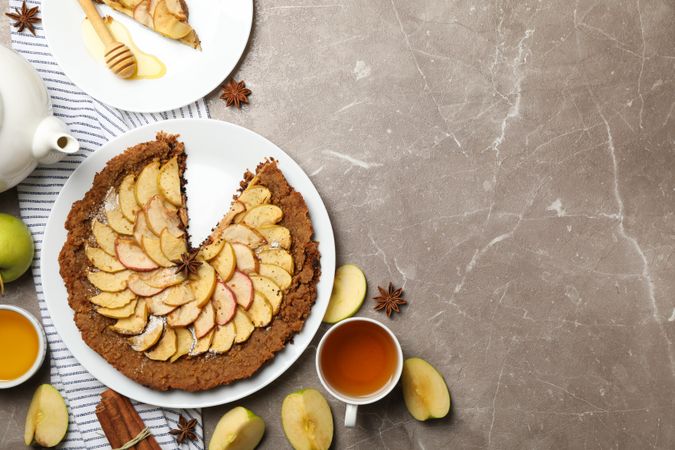 Composition with apple pie and ingredients on gray background, top view
