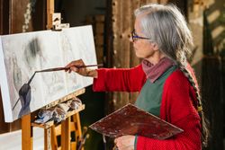 Mature woman painting on canvas in garden