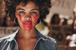 Female activist with a hand print on her mouth, demonstrating violence on women