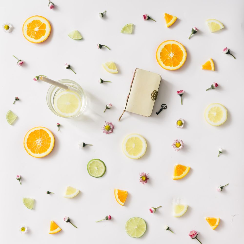 Colorful pattern made of orange, lemon, lime and flowers with lemonade and vintage book with key
