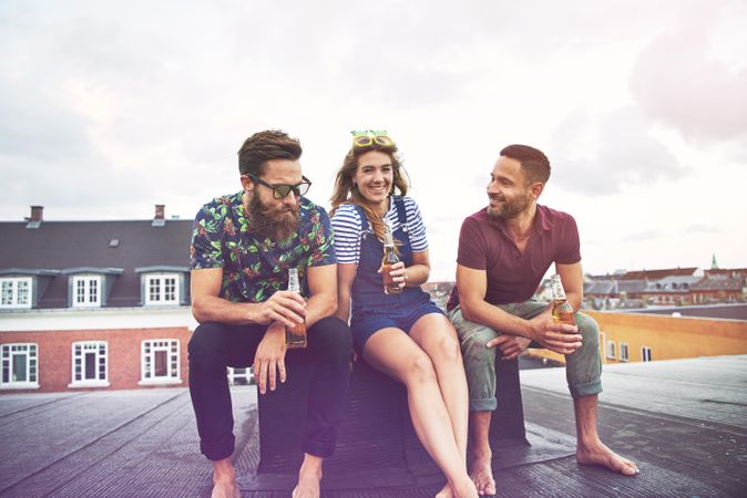 Group of friends relaxing on rooftop with beer