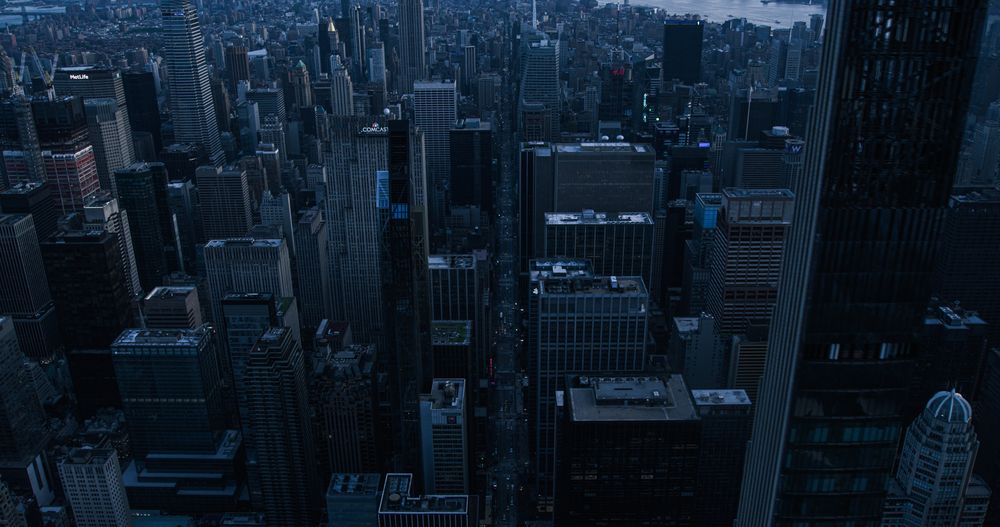 Dark Aerial Evening Photo of New York City with Straight Busy Streets with Cars and Yellow Taxi Vehicles. Lowered Helicopter View of Office Buildings and Skyscrapers in a Big Urban Center