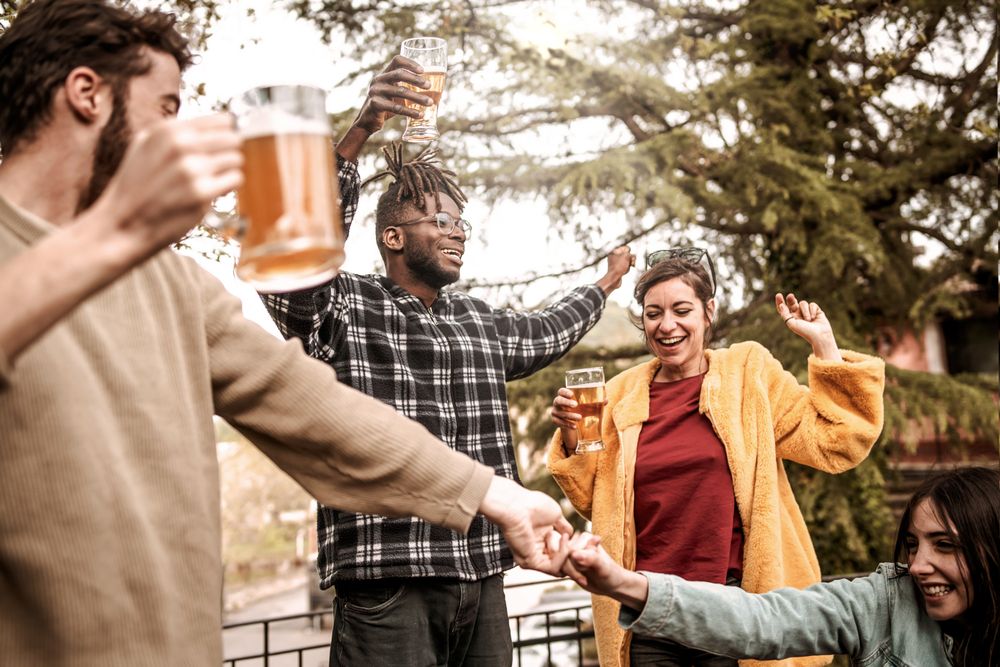 Happy group of diverse multi-ethnic friends drinking beer and having fun together on outdoor dancing party