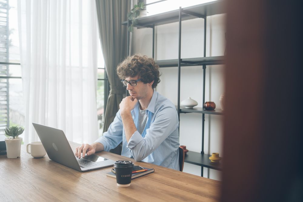 Creative designer reading screen of laptop on his desk