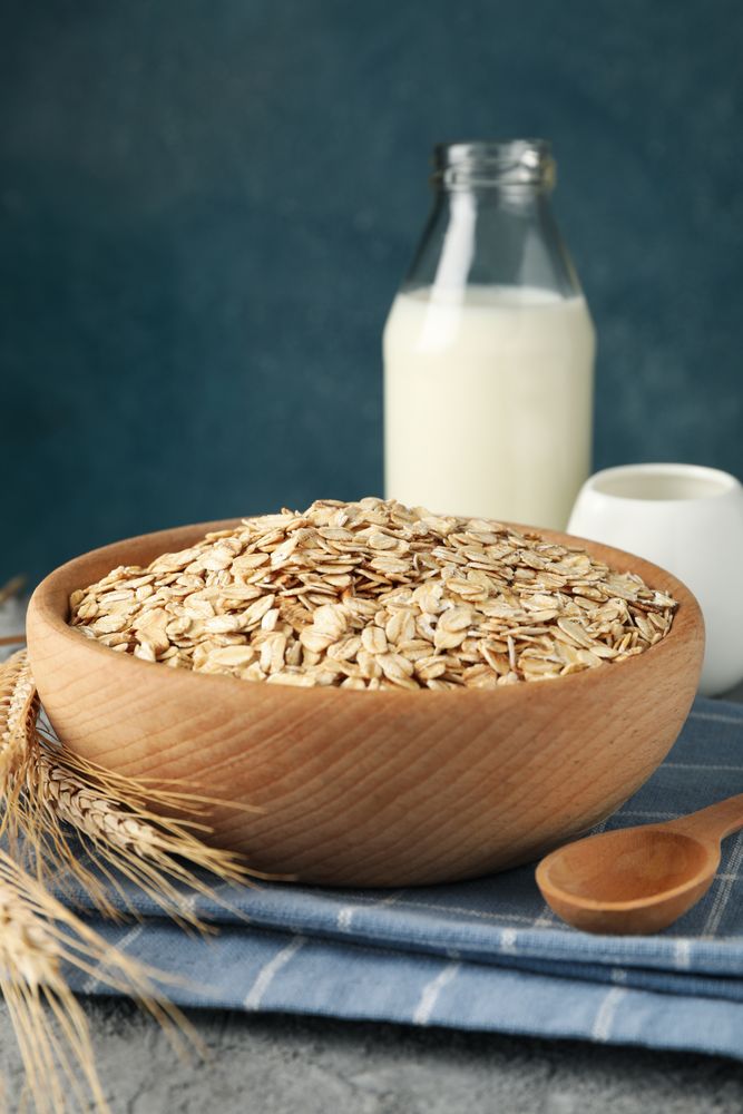 Composition with oatmeal flakes and milk on gray background. Cooking breakfast