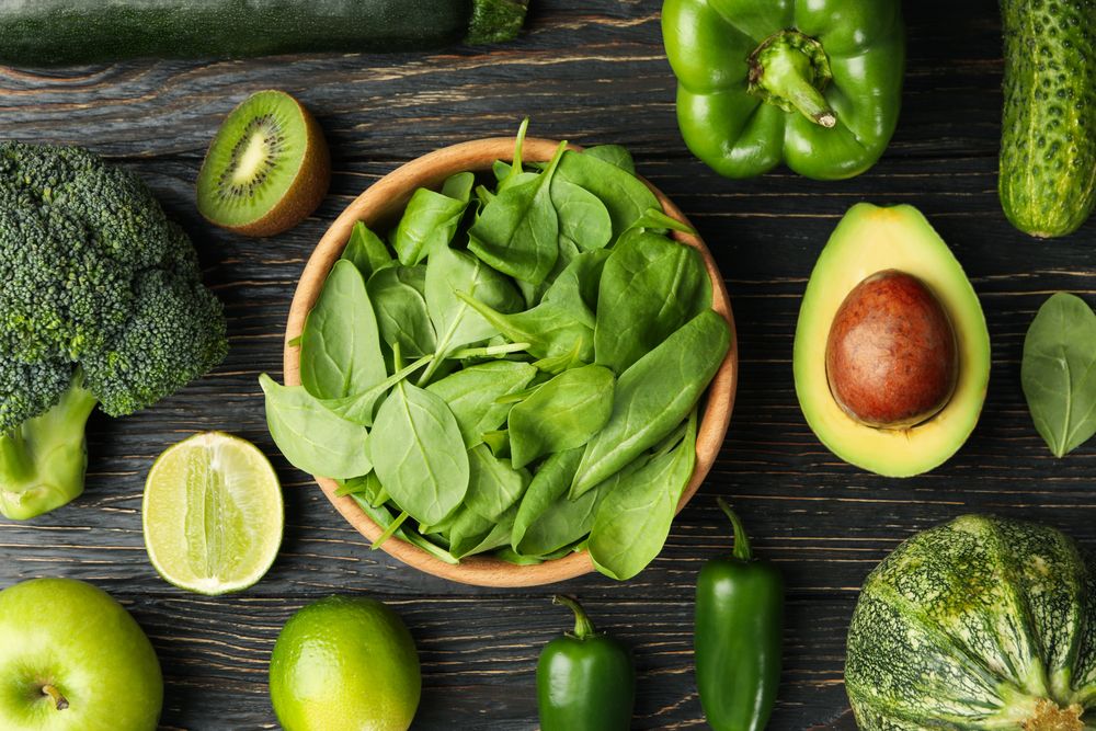 Green vegetables and fruits on wooden background