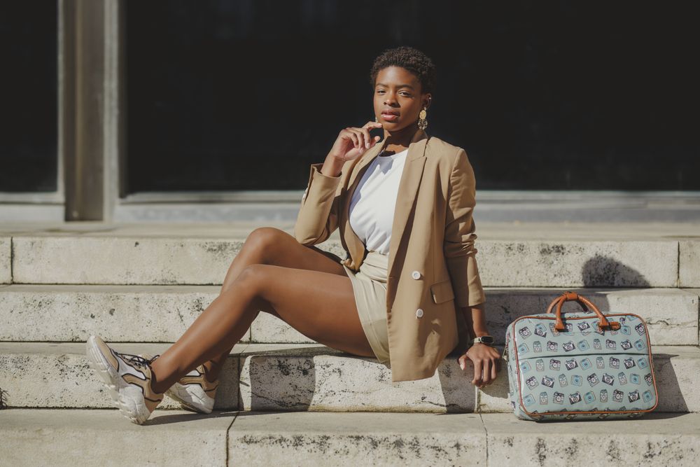 Stylish Black woman with handbag on steps on street