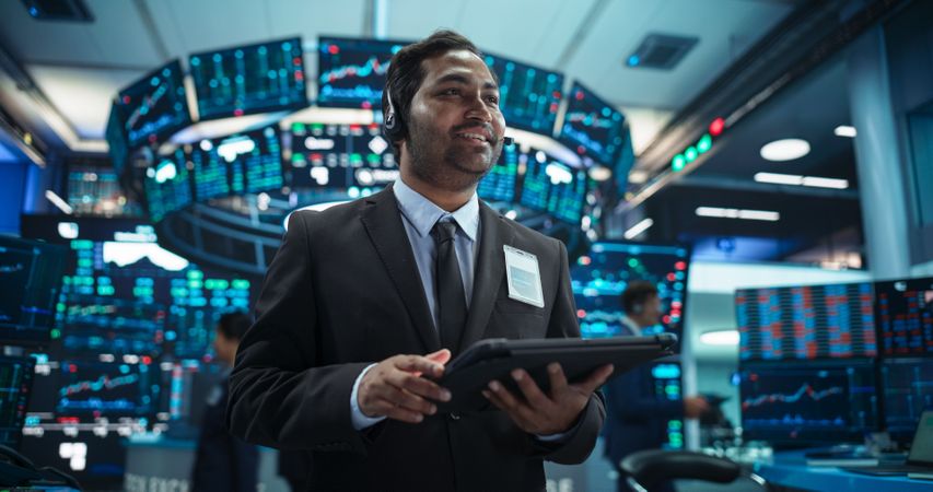 Talented Indian Stock Exchange Investor Working on a Tablet Computer, Day Trading Company Shares, Valuable Technology Investments, Communicating with Clients