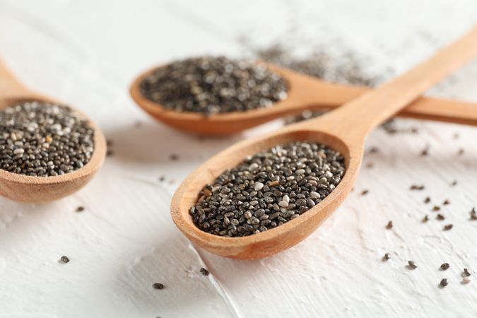 Wooden spoons and chia on neutral background, close up