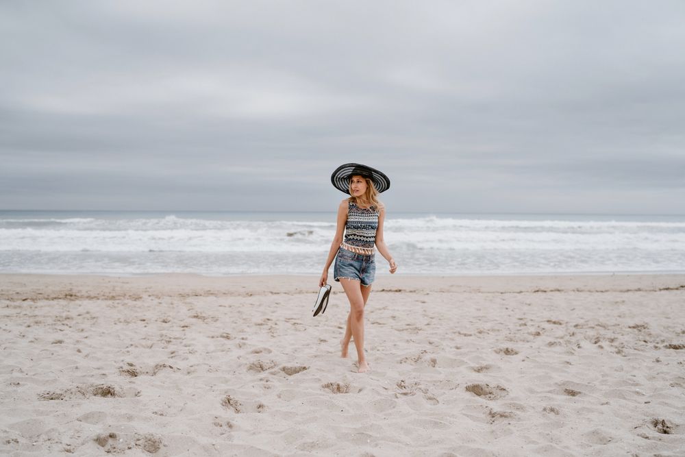 Young female walking barefoot on sandy beach