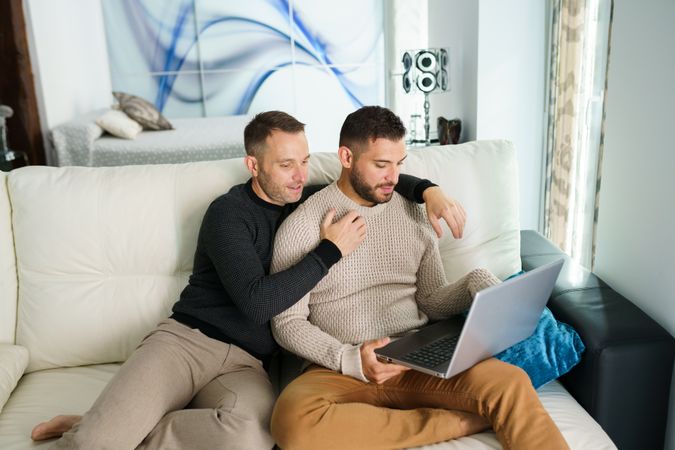 Male couple on laptop together sitting at home