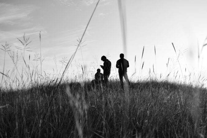 Grayscale photo of three people standing on grass field in Himachal, Pradesh, India