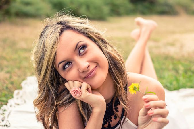 Romantic woman with flower in the hand dreaming outdoors