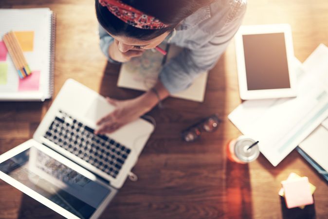 Top view of woman reading on laptop on wooden desk