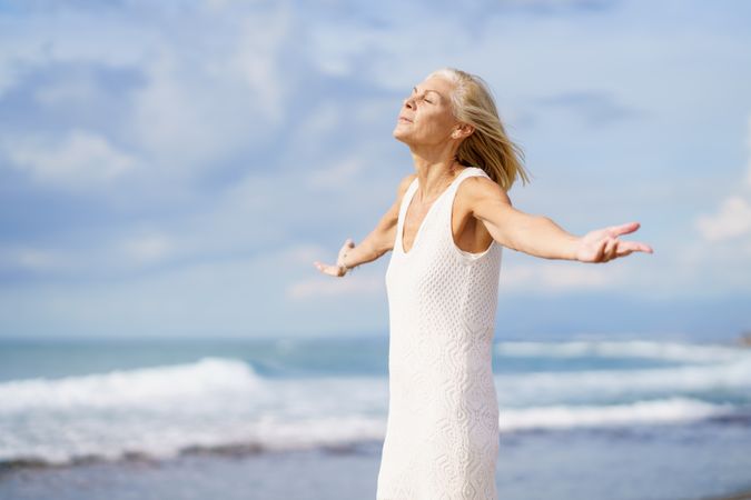 Mature female with open arms facing the ocean