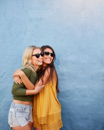Shot of two best friends embracing in front of blue wall