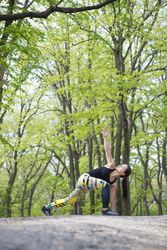 Woman in colorful exercise gear stretching in the forest