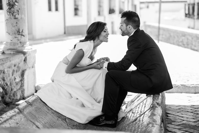 Monochrome shot of happy newlyweds sitting outside