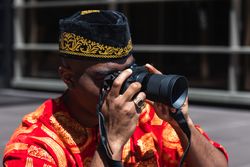 Unrecognizable Black male in traditional clothes taking photo on camera