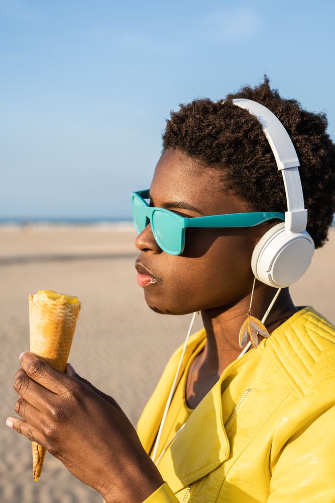 Cool female eating ice cream on beach