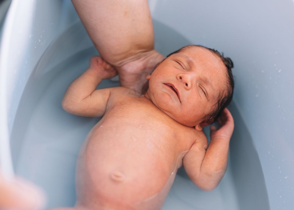 Anonymous parent washing infant in basin