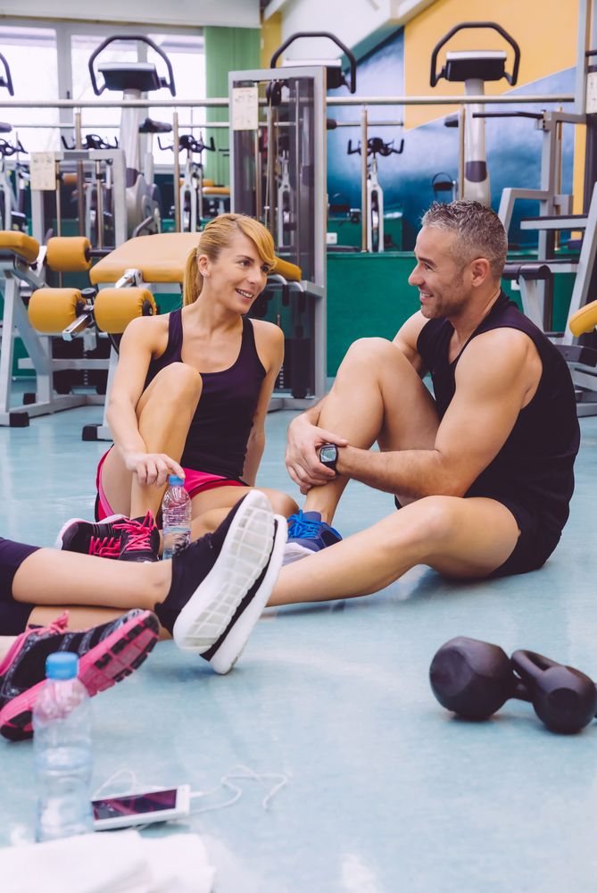 Friends sitting on ground in gym after workout