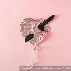 Pink foil heart balloon pierced with plastic knife on pink background 4dqANb