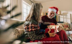 Older couple celebrating Christmas at home and exchanging presents 0yzYO5