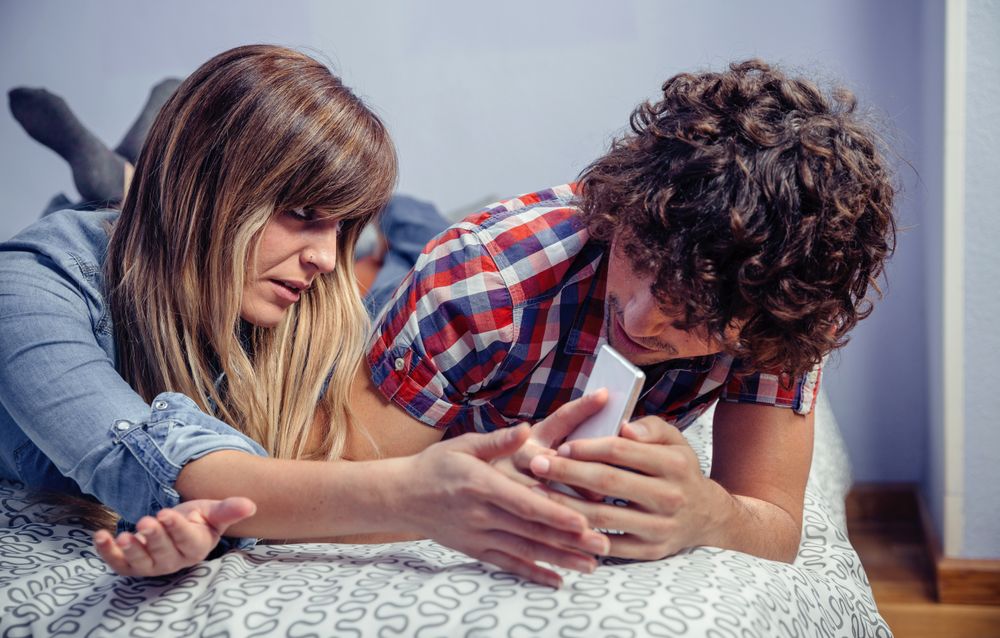 Man hiding messages on smartphone from woman