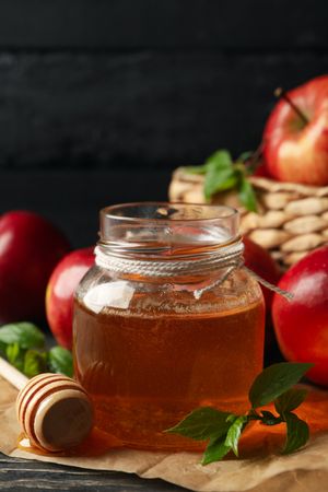 Vertical composition of pot of honey with basket of apples