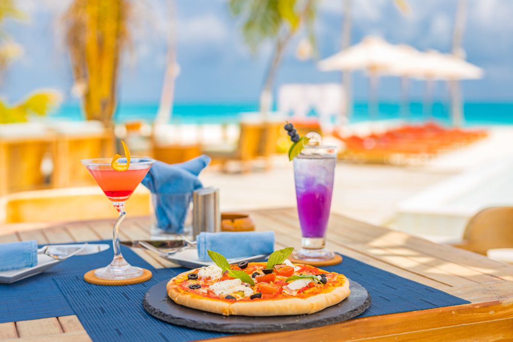 Two cocktails and pizza at an outdoor lunch table