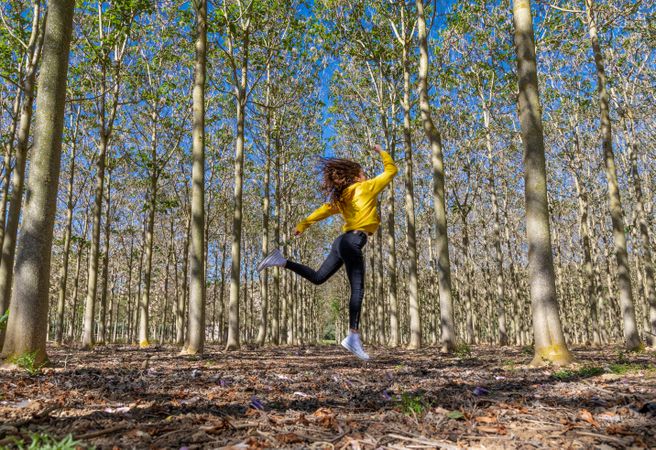 Young sportive female jumping in forest
